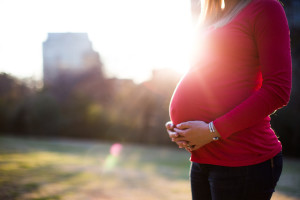 pregnant mom holding her belly with sun in background